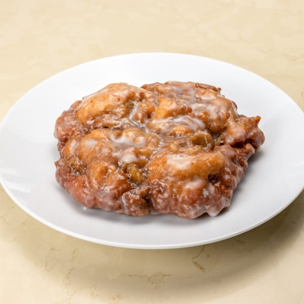 A single glazed Manske Roll from Gil's Broiler, a golden-brown pastry on a white plate.